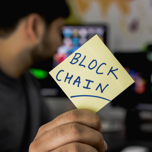 man holding up a sticky note saying blockchain