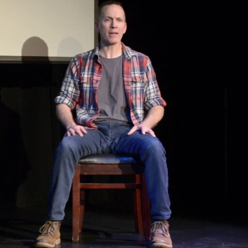 Jay Sefton in the play Unreconciled Jay is seated on a chair on stage speaking